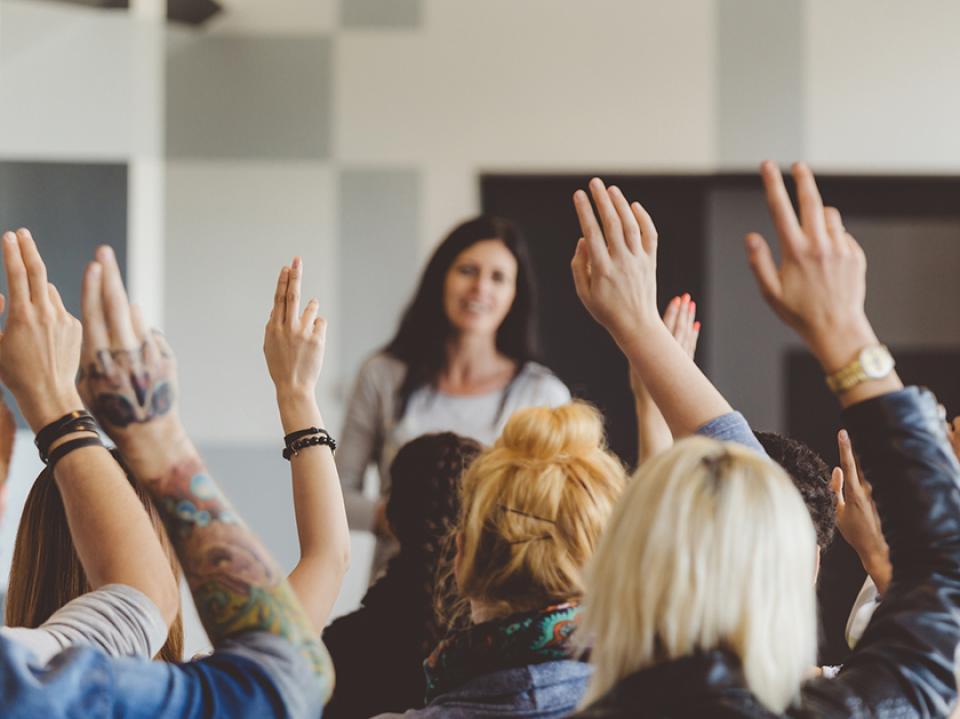 A group with raised hands at a seminar or conference.