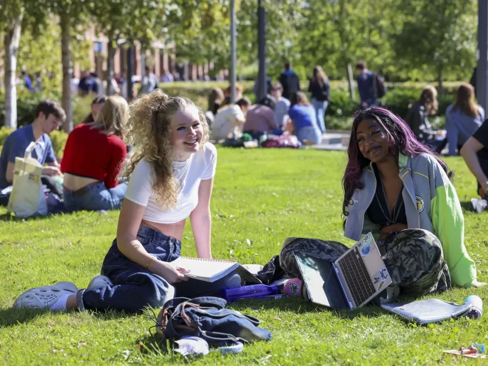 DCU students enjoying the sun sitting on green outside Londis