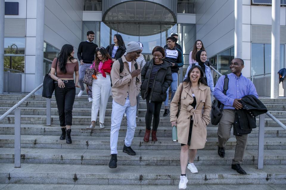 A group of international students walking down a flight on stairs, smiling and laughing along the way.