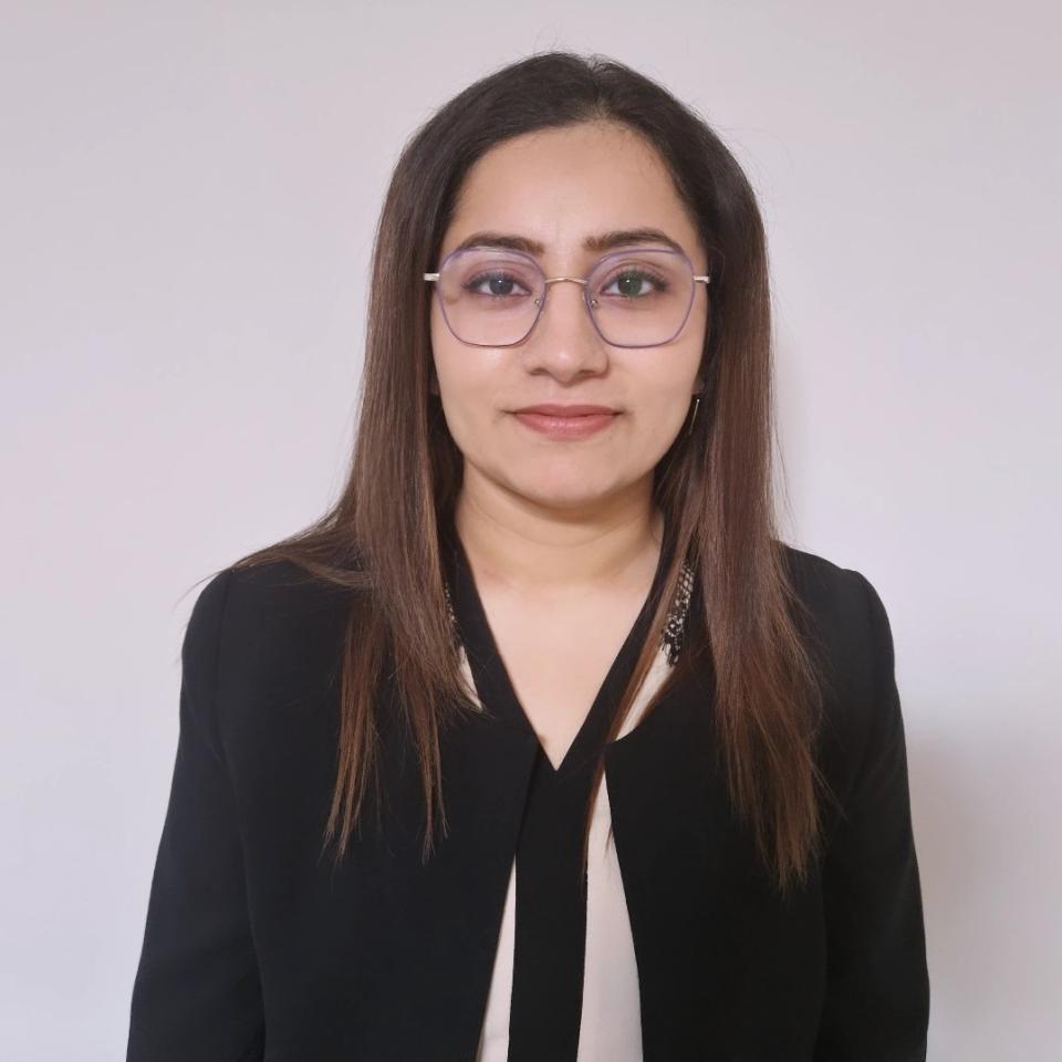 A professional headshot of Akanksha Mehta, a woman with brown hair and glasses wearing a black blouse.