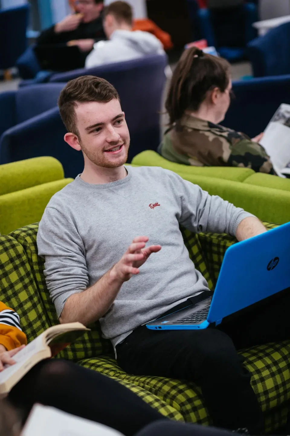 A male student talking with his laptop open.