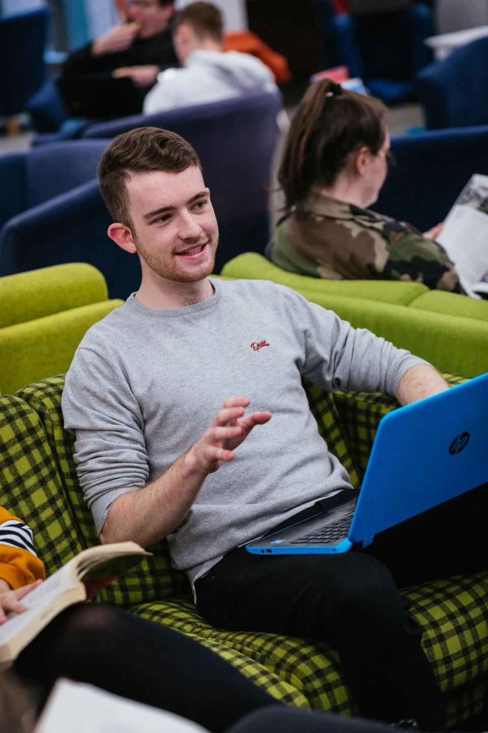 A male student talking with his laptop open.