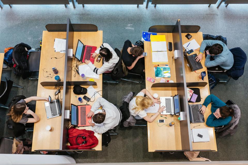 Students at different desks studying in the library.