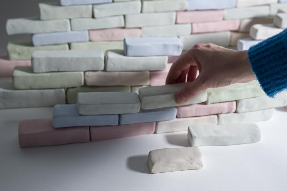 Pink, Green and Blue bricks made from clay stacked side by side and on top of eachother