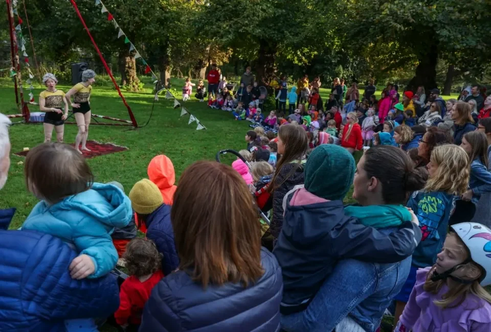 Two performers stand in front of a crowd taking to the audience