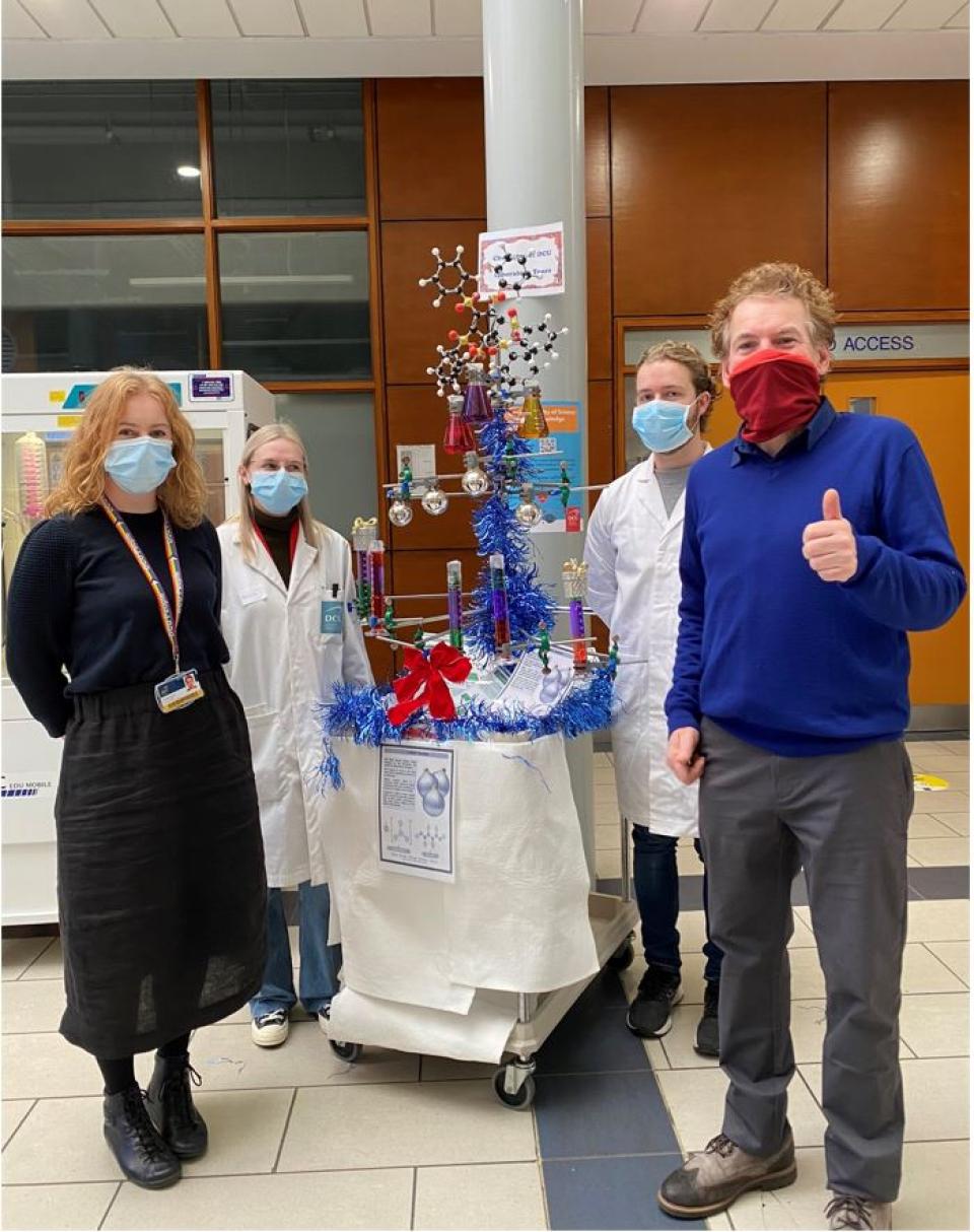 DCU Staff at the open day in front of a stand with chemical models and a colourful Christmas tree