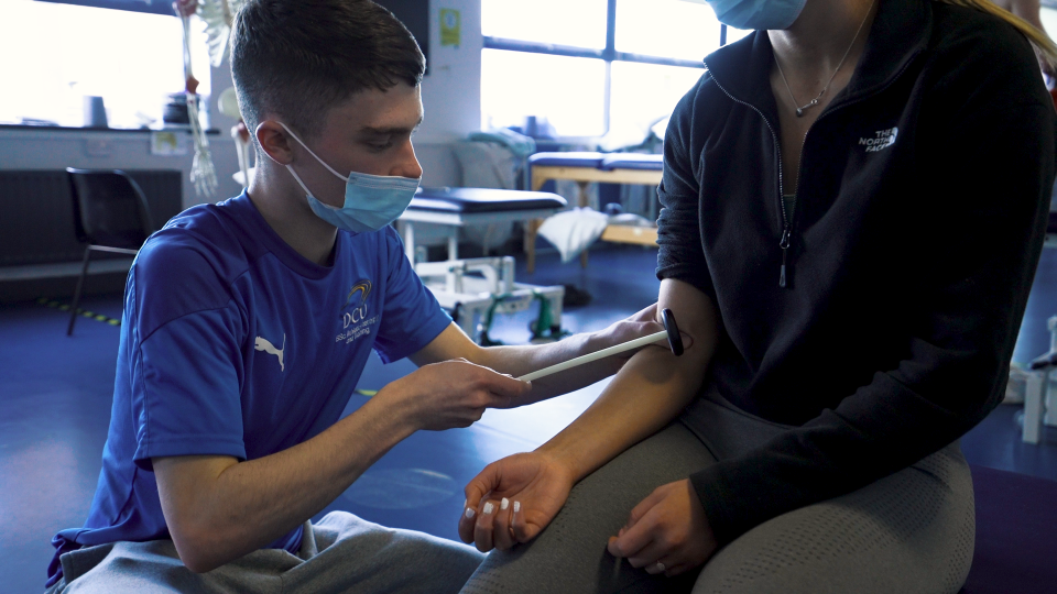 Student using a reflex hammer on a classmate to test for elbow flexor reflexes