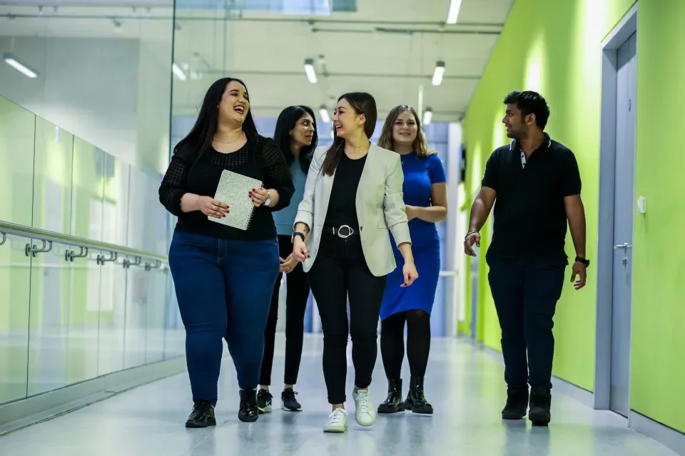 Five students walking down a corridor in DCU talking to one another