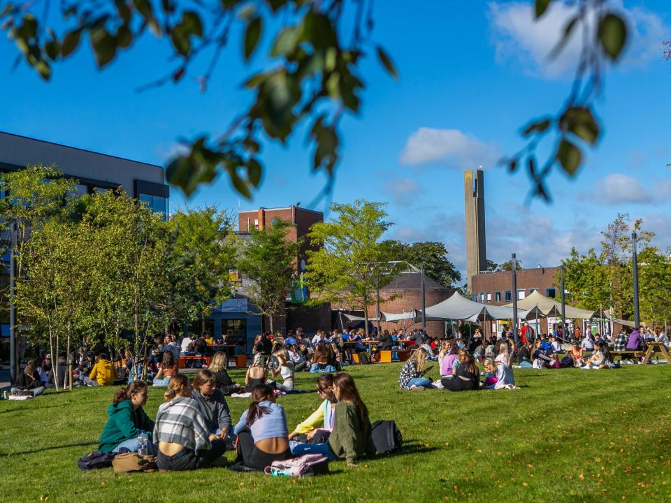 Image shows students sitting outside