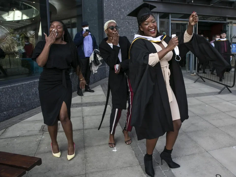 Three people celebrate graduation with a dance