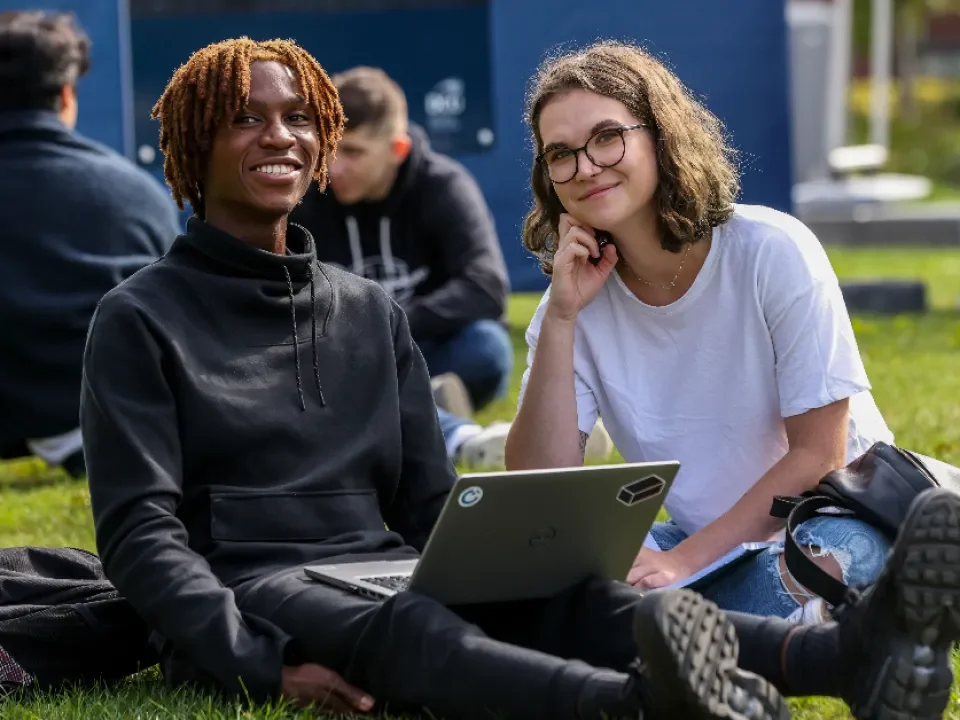 Two students sit on the grass