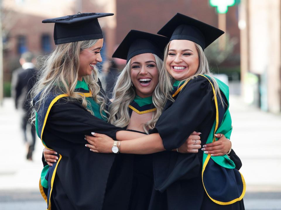 Three female graduates hug for a photograph