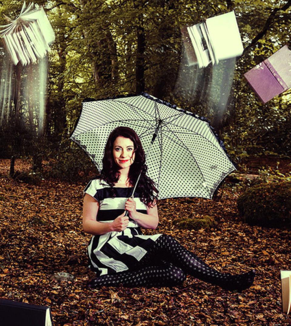 Woman sitting under a tree holding an umbrella. Books are falling from the sky.