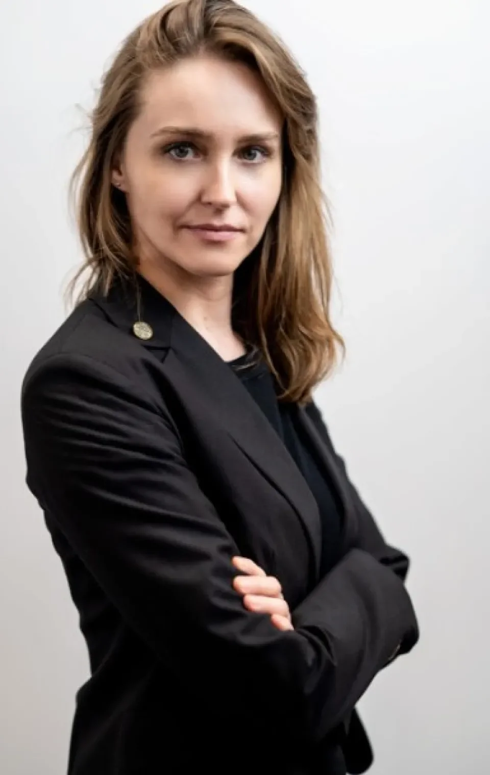 woman with brown hair in a black jacket against white background