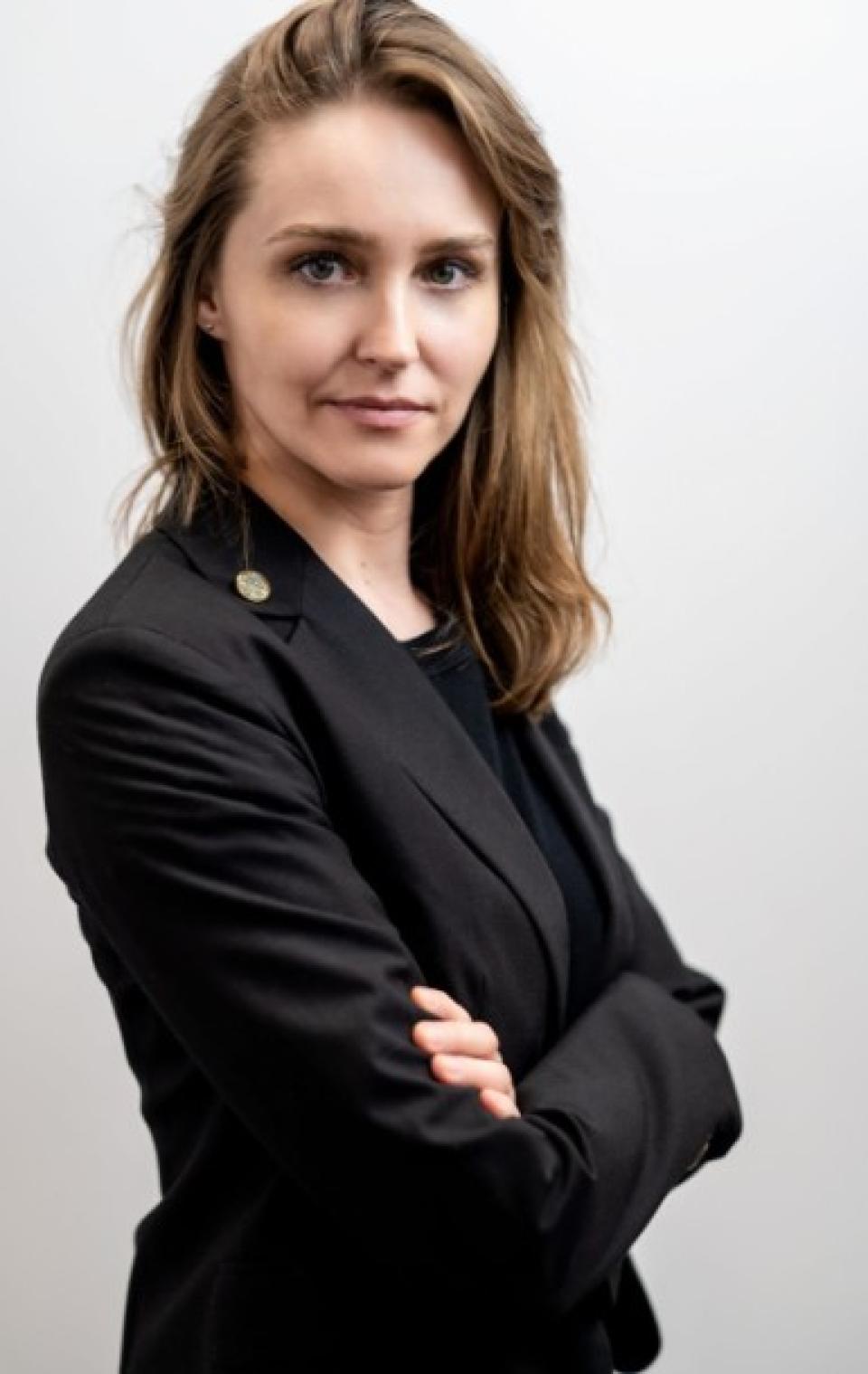 woman with brown hair in a black jacket against white background