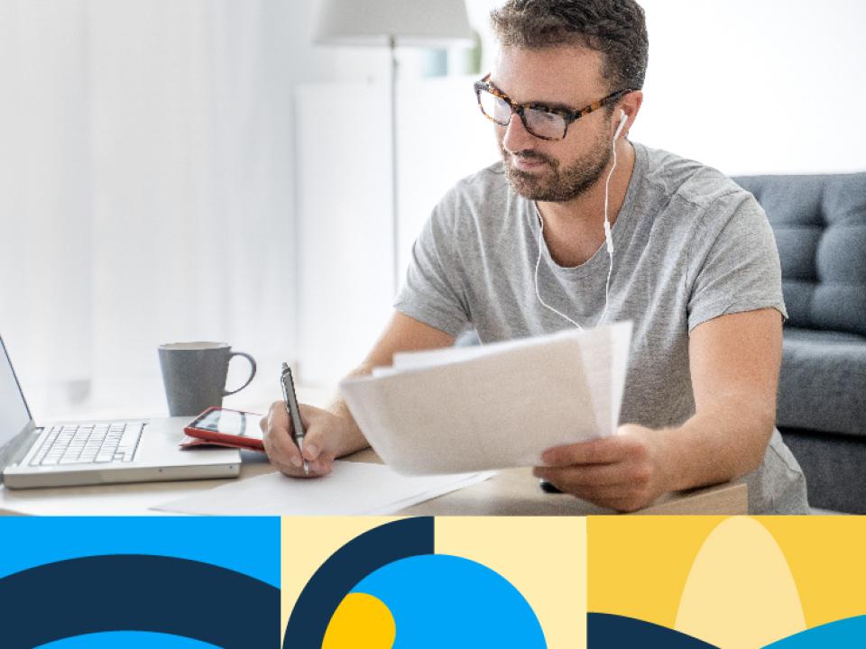 Shows man taking notes while watching laptop and listening to audio