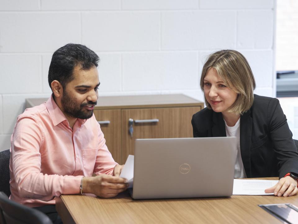 Manager and team member looking at a laptop