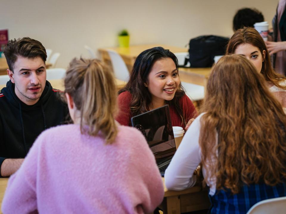Five students chatting at a table