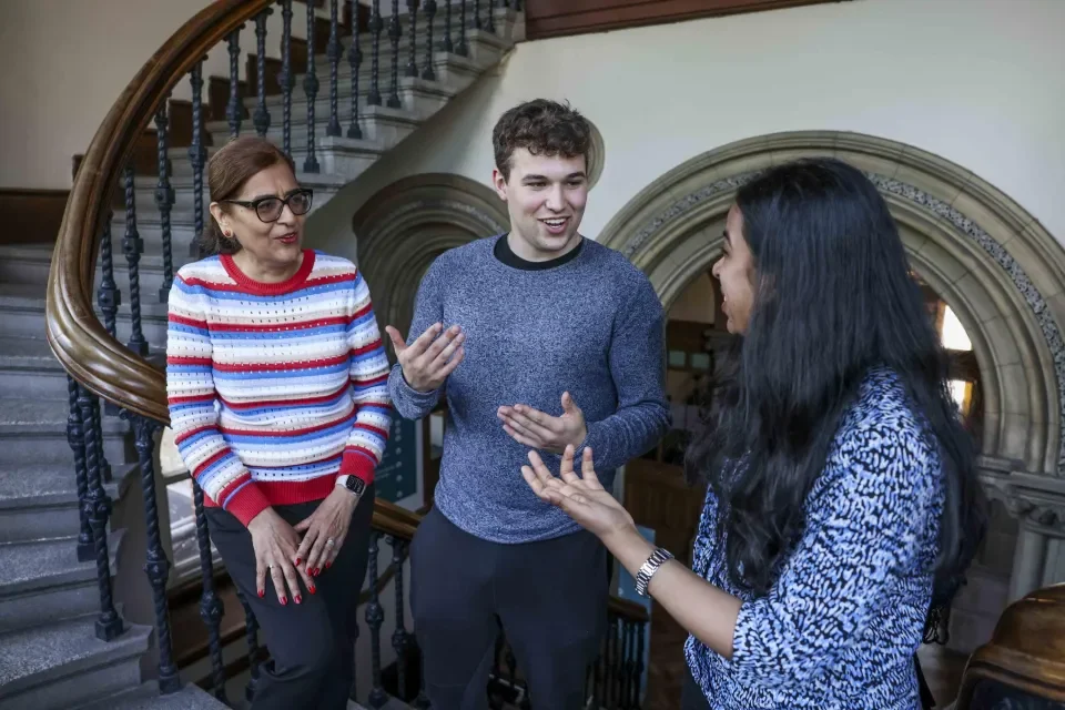 Three people talking at the bottom of a stairs