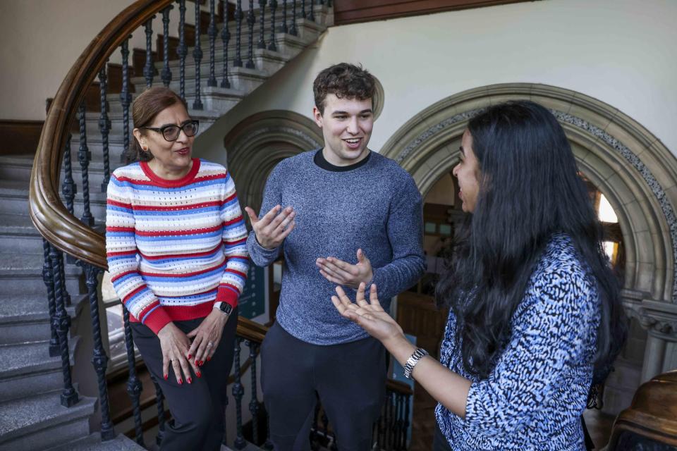 Three people talking at the bottom of a stairs