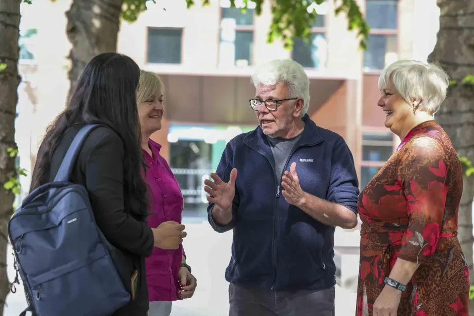 4 people having a conversation in the sunshine