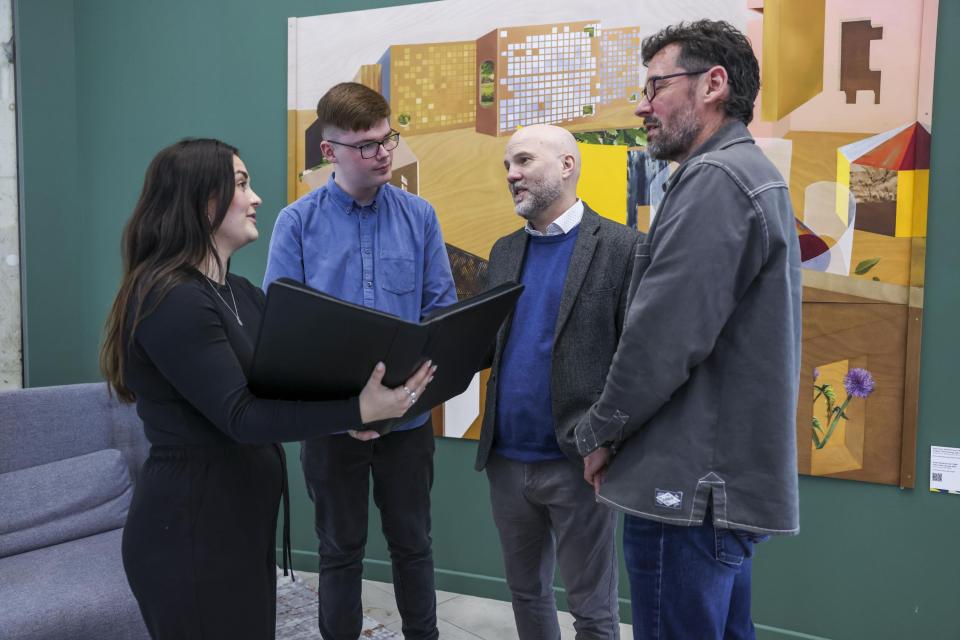 four people talking in front of a painting
