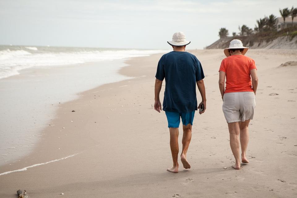 Two retired people walking on the beach.