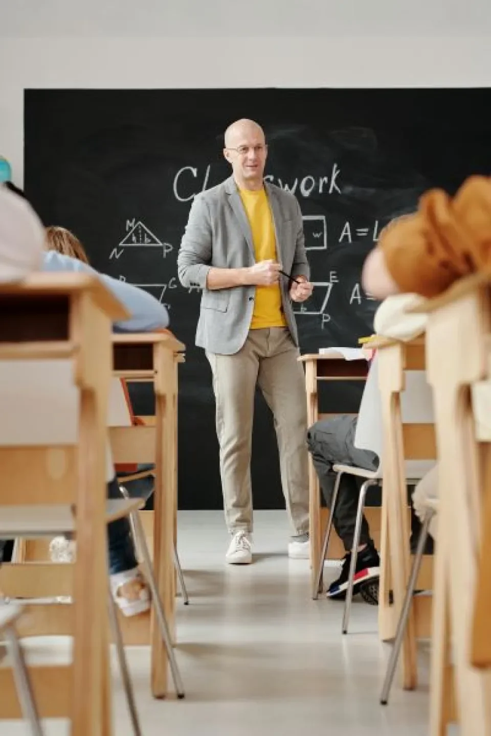 Man teaching a class, standing in front of a blackboard.