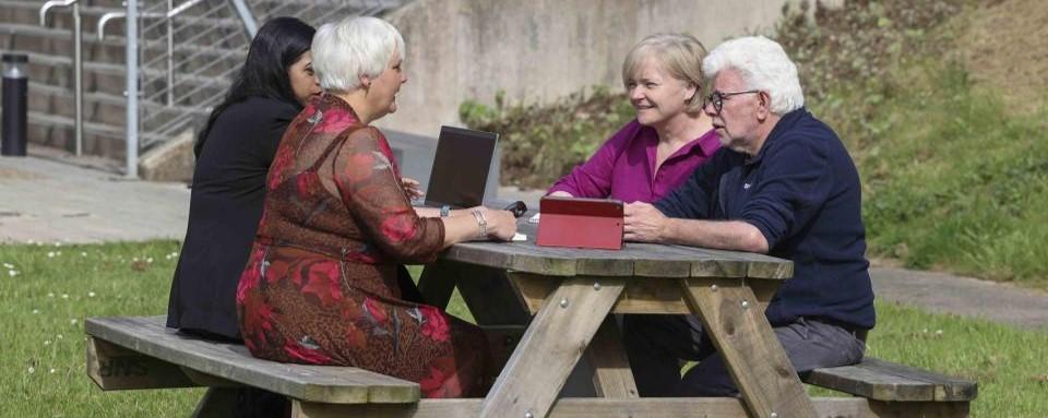 DCU colleagues chatting on table on St. Patricks, Campus