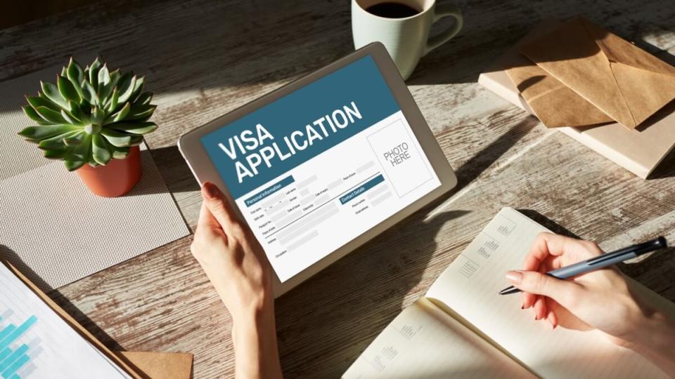 Hands holding a tablet with a visa application on the screen