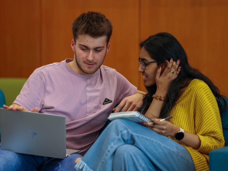 Shows male and female students sitting together looking at laptop in DCU's O'Reilly Library