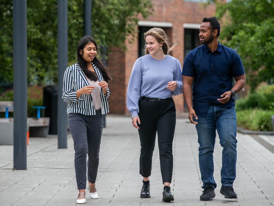 Shows three postgraduate students walking on DCU's Glasnevin campus