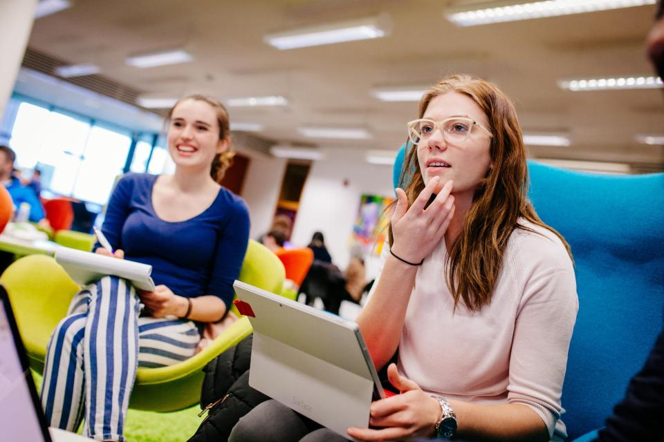 students on laptops at a desk in the library