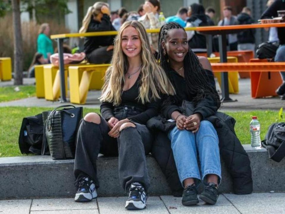 2 students sitting outside the U building on Glasnevin campus