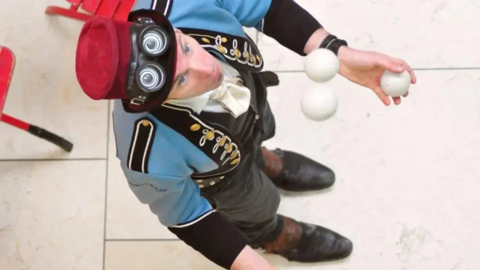 Juggler wearing red hat and blue jacket