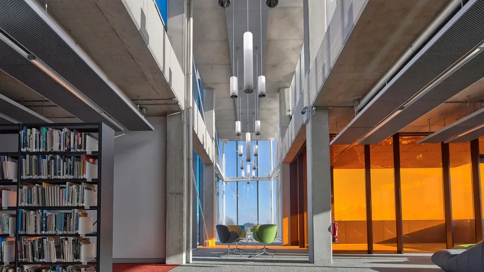 Inside Cregan Library building with books on the left side of the image and orange windows on the right