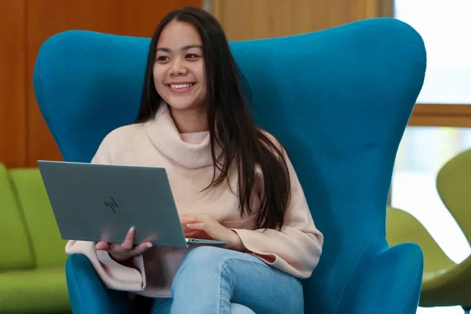 A woman sitting on a chair holding a laptop