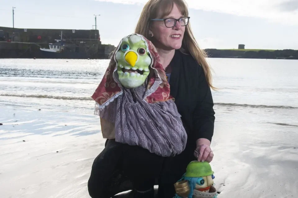 Artist Cliodhna Noonan holding a puppet with a green face 