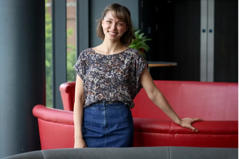 Dancer Mia Di Chiaro smiling, standing in front of a red couch
