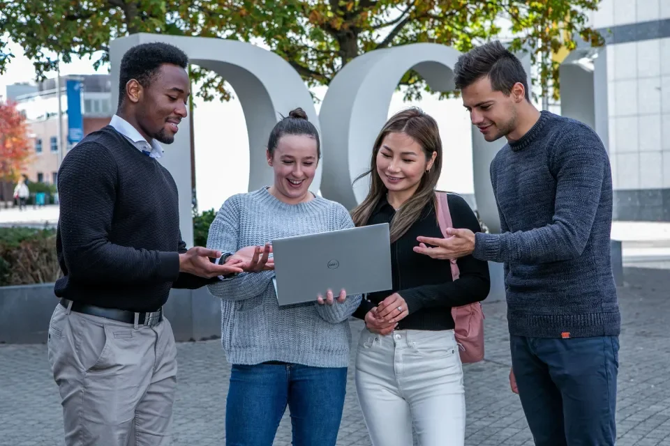 four students looking at a laptop on DCU Glasnevin campus