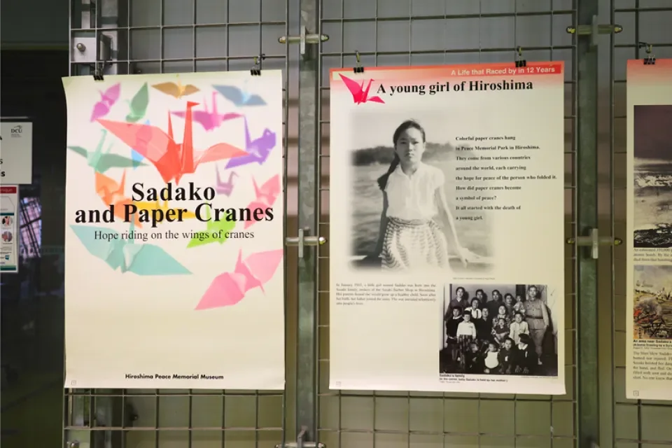 Two posters on a grid. The first poster has the title Sadako and Paper Cranes exhibition: Hope Riding on the Wings of Cranes. The second has the title A Young Girl of Hiroshima over a picture of a young girl.