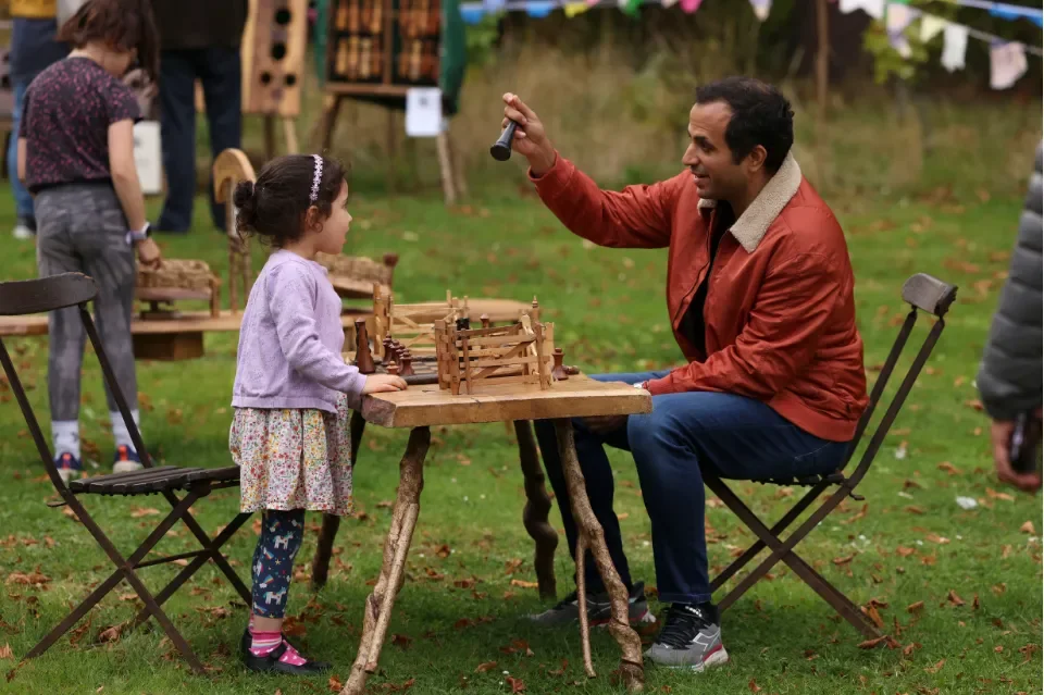Child and man playing with a chess board handmade from wood