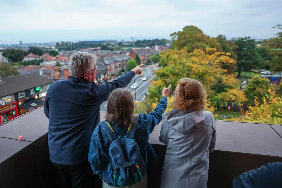 Three people standing on a balcony looking out over Drumcondra