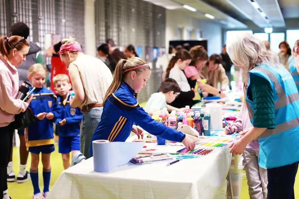 Young people gather around a table creating badges and pictures