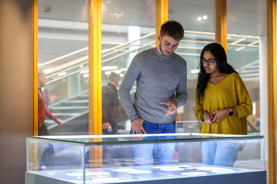 Two people looking at a exhibition displayed in a glass case