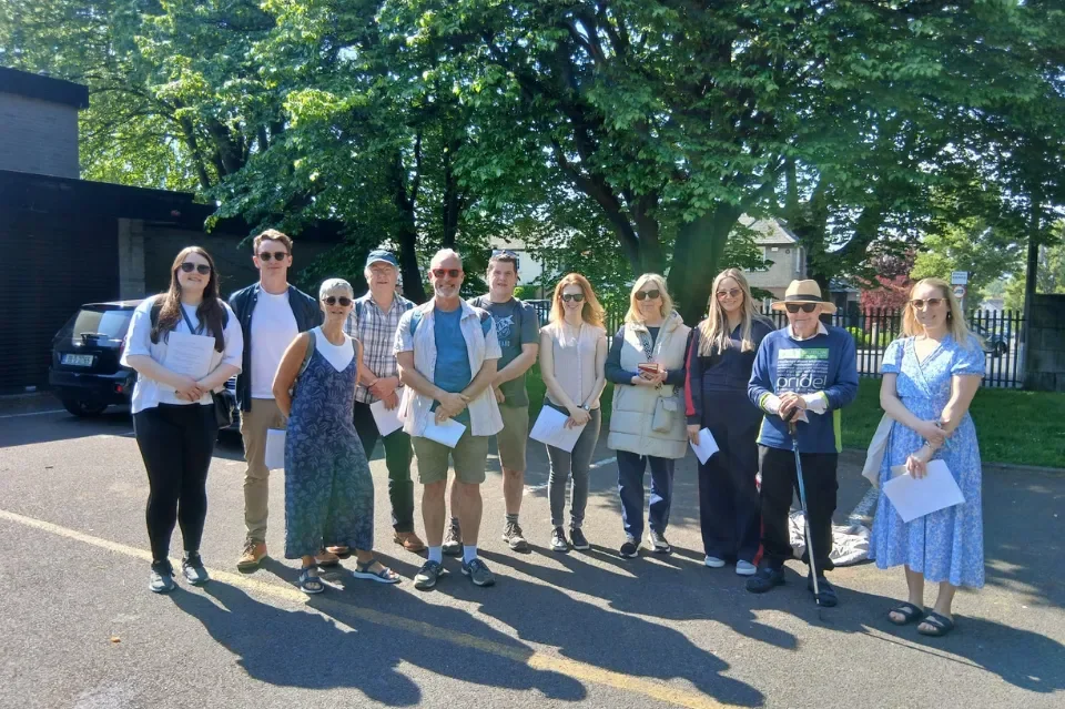 Group of 11 people, men & women standing in a line in the sun