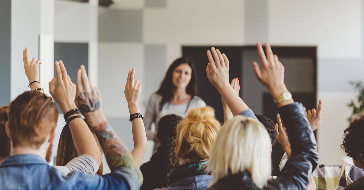 A group with raised hands at a seminar or conference.