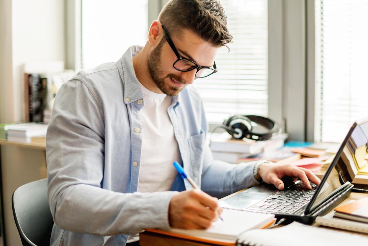 Male student writing at his laptop