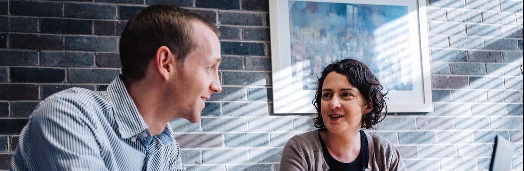 Man and woman sitting at desk having conversation