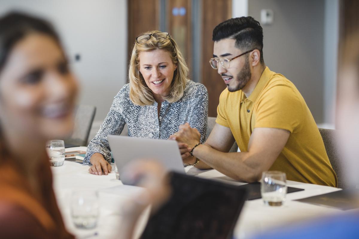 Two people working together looking at a laptop.